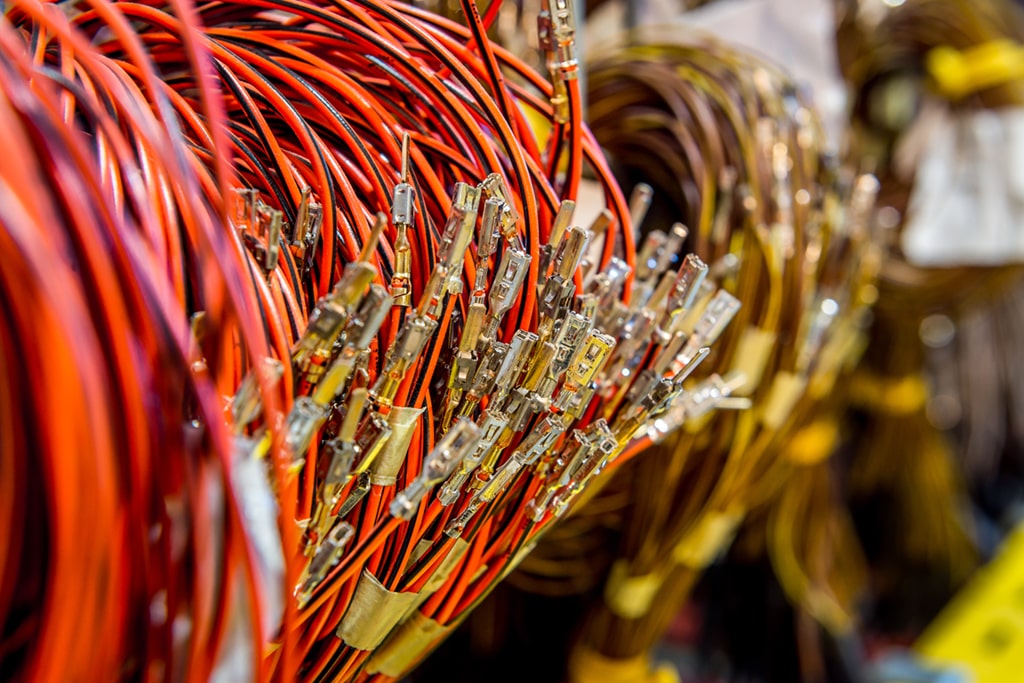 Close-up of organized bundles of red wires with connectors in an automobile wire harness assembly.