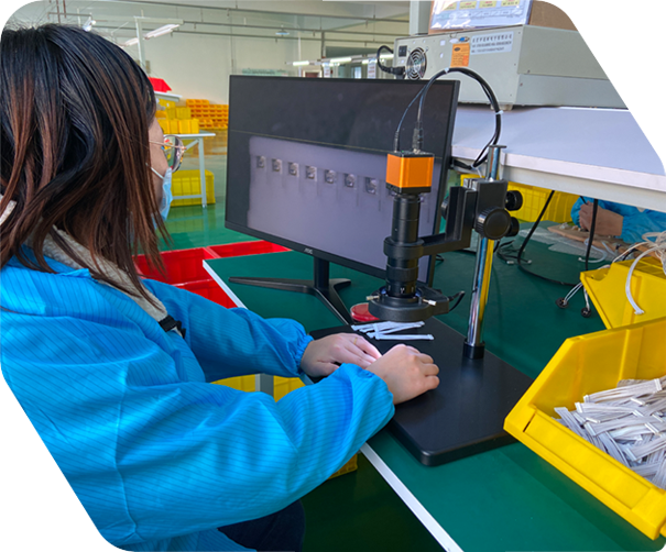 Worker inspecting cable assembly components under a magnification tool