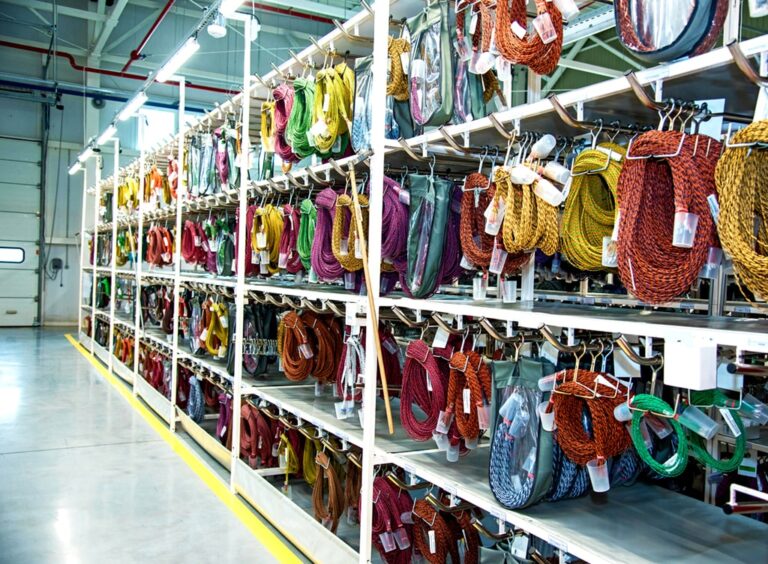 Rows of neatly organized wire harnesses in various colors hanging in a warehouse.